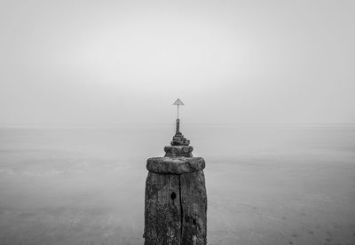 Lighthouse by sea against clear sky