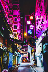 Low angle view of illuminated street amidst buildings at night