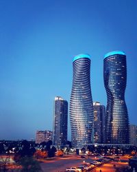 Illuminated cityscape against clear blue sky