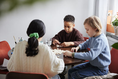 Girl and boys playing scrabble at dining table