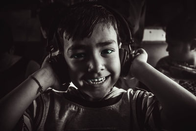 Close-up portrait of smiling boy listening music through headphones