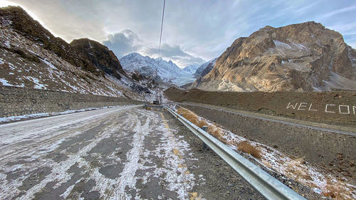 Road amidst snowcapped mountains against sky during winter