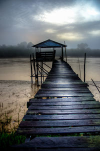 Pier on sea against cloudy sky