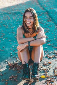 Portrait of smiling young woman sitting on pavement