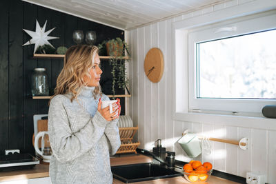 Side view of young woman standing at home