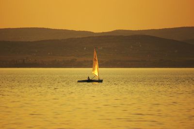 Silhouette sailboat sailing on lake against sky during sunset