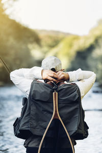 Man holding backpack standing by river