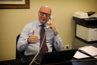 Happy manager gesturing thumbs up while talking on phone in office