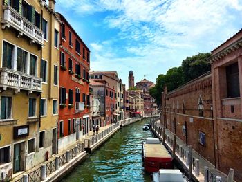 Canal amidst city against sky