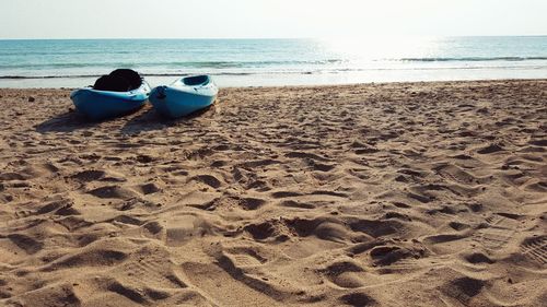 Canoes moored at beach against clear sky