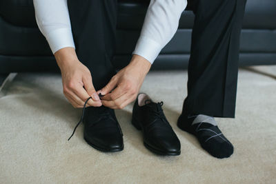 Low section of businessman wearing dress shoes at home