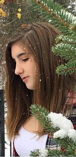 Portrait of young woman standing against plants