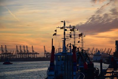 Sailboats moored at harbor against sky during sunset