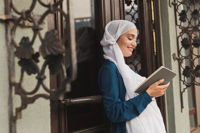 Young woman looking through window