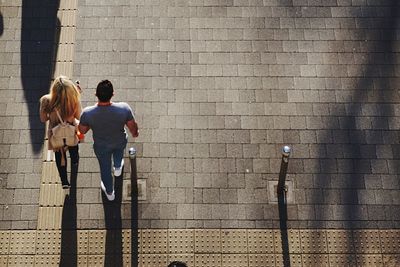 High angle view of man and woman walking on sidewalk during sunny day