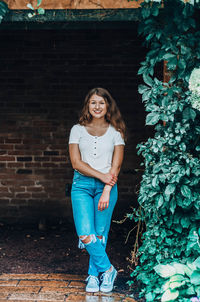 Portrait of smiling girl standing against brick wall