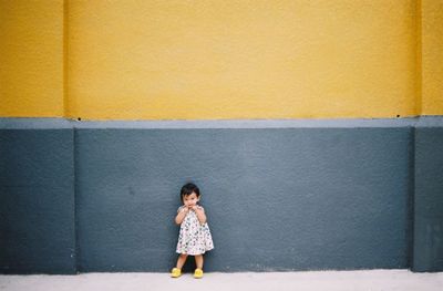 Full length of a woman standing against yellow wall