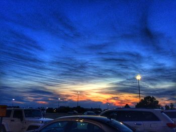 Cars on road against sky at sunset