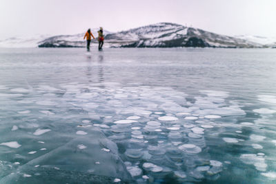 People standing on ice covered lake