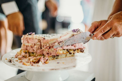 Cropped hands serving cake in plate at wedding ceremony