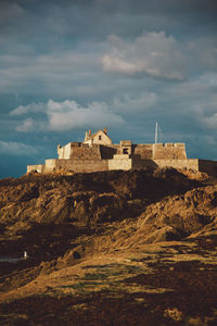 Castle by rocks against sky