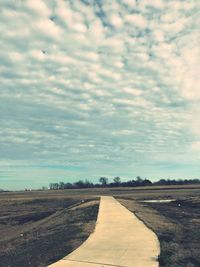 Road amidst agricultural field against sky