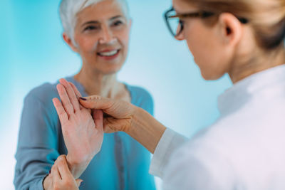 Doctor doing carpal tunnel syndrome test with a senior woman.