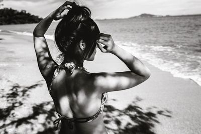 Young woman standing on beach against sky