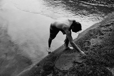 High angle view of shirtless mature man making heart shape on sand at beach