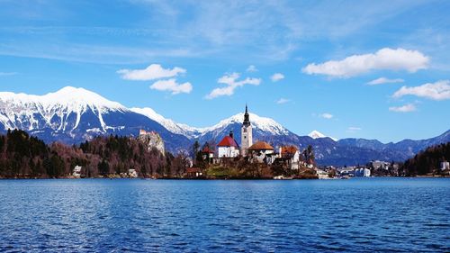 Scenic view of buildings by snowcapped mountains against sky