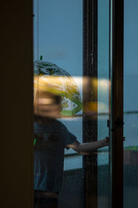 Rear view of man standing by window