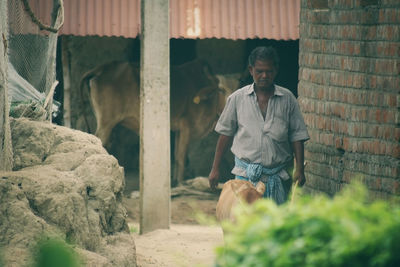 Side view of young man standing against rock