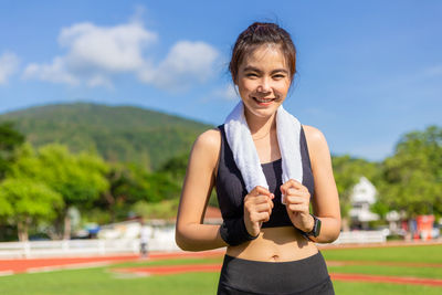 Portrait of smiling young woman standing against sky