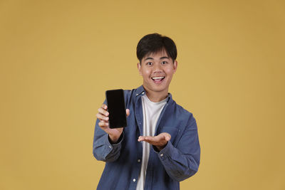 Portrait of a smiling young man holding camera