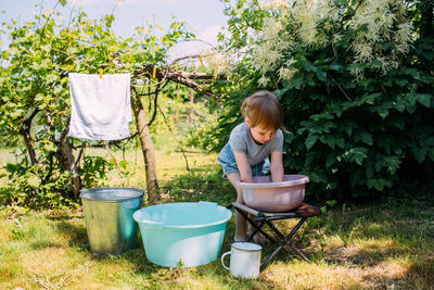 Little preschool girl helps with laundry. child washes clothes in garden