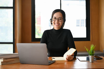 Portrait of young woman using laptop at office