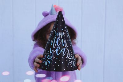 Close-up of girl holding party hat against wall