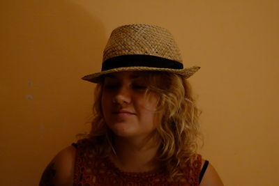 Close-up portrait of young woman wearing hat against yellow background