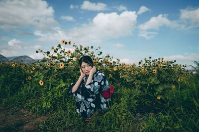 Low section of woman with red flowers on field