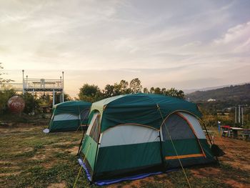Landscape of pitch tents on the hill against sky during sunset