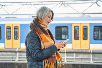 Side view of woman standing against train