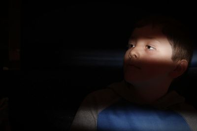 Cute boy looking away in darkroom