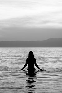 Silhouette woman in sea against sky