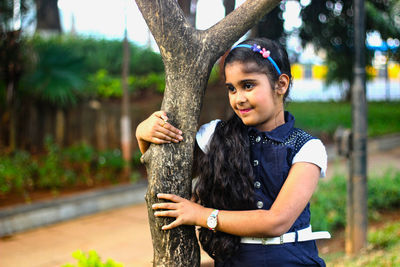 Girl looking away white embracing tree trunk