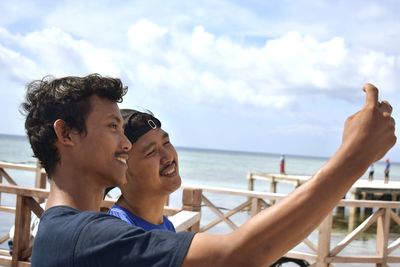 Friends taking selfie by sea against sky