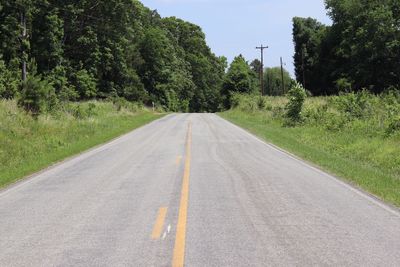 Road amidst trees on landscape against sky