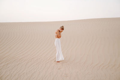 Full length of woman standing on sand dune