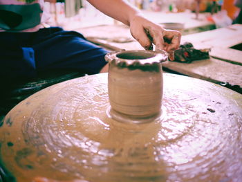 Midsection of woman shaping earthenware on pottery wheel