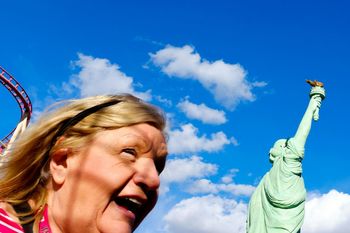 LOW ANGLE VIEW OF WOMAN STANDING AGAINST BLUE SKY