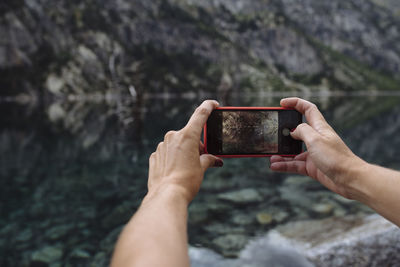 Close up of hands taking a photo with cellphone of landscape.